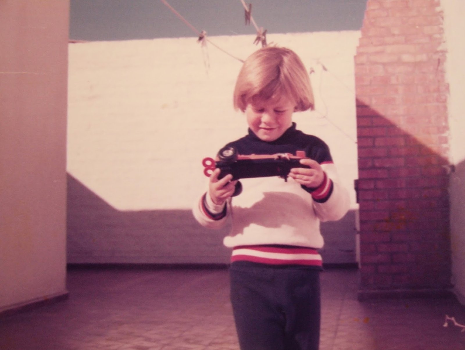 Sebastian as a child on a rooftop, holding a little electronic car