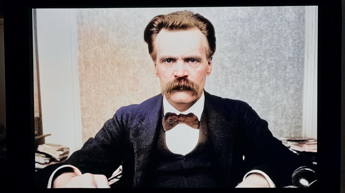 Nietzsche on screen during a live stream, sitting at his desk and looking at the camera.